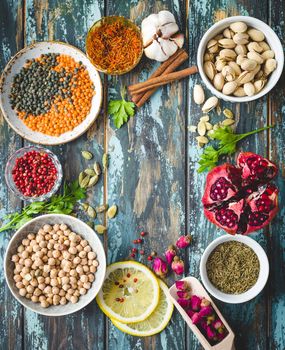 Arab ingredients for middle eastern food. Arabic cuisine ingredients. Background. Chickpea, lentils, rose buds, lemon, spices, pomegranate, pistachios. Halal food making. Space for text. Top view