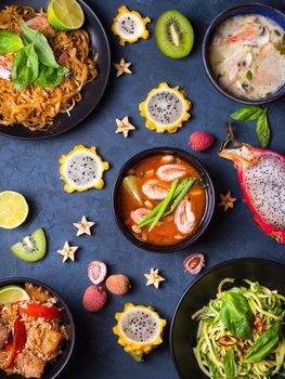 Assorted Thai food. Traditional dishes of Thai cuisine. Tom yum, tom kha gai, pad thai noodles, thai fried rice with pork and vegetables khao phat mu, green papaya salad som tam, thai fruits. Top view