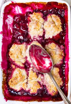 Close-up of delicious homemade cherry cobbler pie with flaky crust. With a vintage spoon. Top view