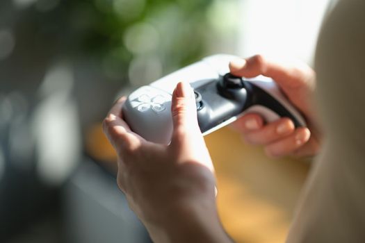 Beautiful female hands hold a joystick for the game, close-up. Video game addiction, gaming accessories, device