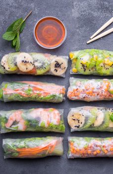 Fresh assorted spring rolls set. Handmade asian/Chinese spring rolls. Rustic concrete background. Spring rolls with shrimps, vegetables, fruits. Top view. Healthy asian food. Lunch/snacks/buffet