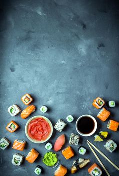 Japanese sushi on a dark background. Sushi rolls, nigiri, maki, pickled ginger, wasabi, soy sauce. Sushi set on a table. Space for text. Top view. Sushi background. Asian or Japanese food frame. Toned