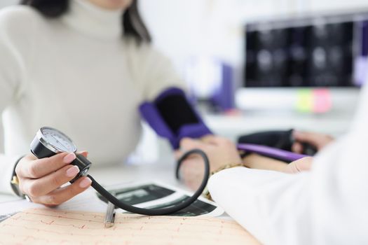 Close-up of female hand holding tonometer. Practitioner examining patient and measuring blood pressure. Doctors consultation idea. Healthcare and medicine concept