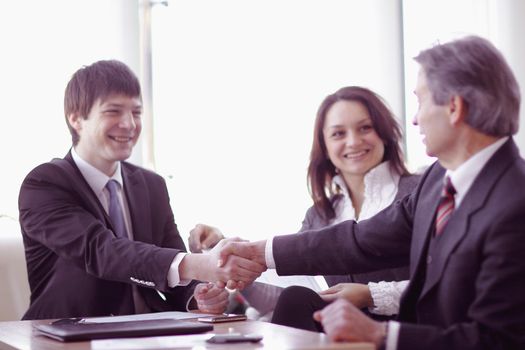 handshake of business partners sitting at a Desk . the concept of partnership