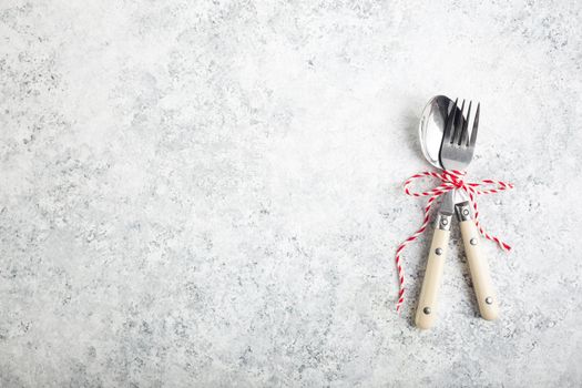 Christmas/New Year background. Christmas table place setting. Festive dinner background. Spoon, fork, white concrete background. Christmas decoration. Space for text. Top view. Holidays. Greeting card