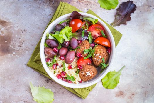 Healthy vegetarian salad with falafel, bulgur, olives, tomatoes, parsley. Healthy buddha bowl salad. Middle eastern style salad. Vegan/vegetarian food. Fresh lunch/dinner. Top view. Iron background