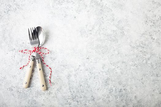 Christmas/New Year background. Christmas table place setting. Festive dinner background. Spoon, fork, white concrete background. Christmas decoration. Space for text. Top view. Holidays. Greeting card