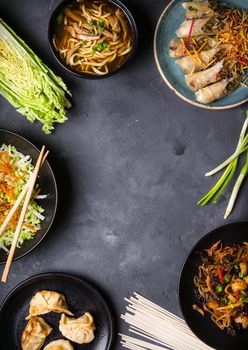 Chinese food dark background. Chinese noodles, fried rice, noodle soup, dim sum, spring rolls, salad. Traditional Chinese cuisine dishes set. Space for text. Top view. Chinese restaurant concept