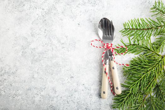 Christmas/New Year background. Christmas table place setting. Festive dinner background. Spoon, fork, fir branch on white concrete background. Christmas decoration. Space for text. Top view. Holidays