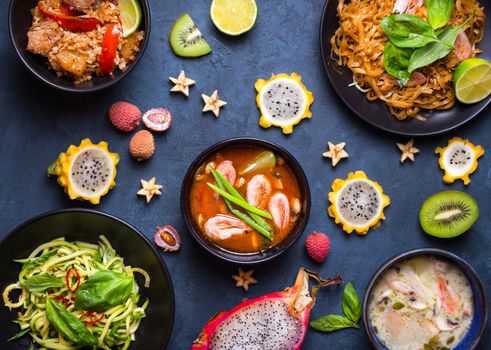 Assorted Thai food. Traditional dishes of Thai cuisine. Tom yum, tom kha gai, pad thai noodles, thai fried rice with pork and vegetables khao phat mu, green papaya salad som tam, thai fruits. Top view