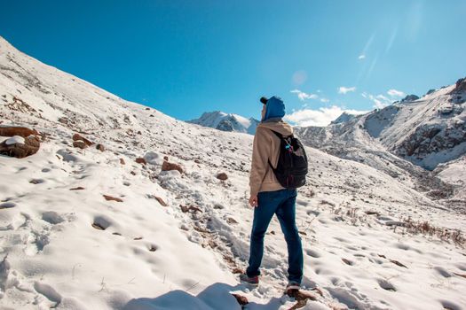 The guy on the slope of the snow mountain looks into the sky. Sky with white clouds.