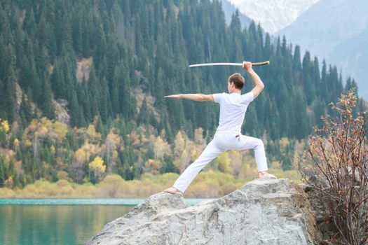 A man with a Japanese sword took up a fighting stance. Training in the mountains.