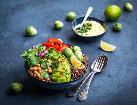 Bowl with healthy salad and dip. Close-up. Buddha bowl with chickpea, avocado, quinoa seeds, red bell pepper, fresh spinach, brussels sprout, lime mix. Vegetarian salad. Clean healthy eating concept