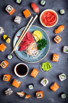 Japanese sushi on a rustic dark background. Sushi rolls, sashimi, nigiri, maki, pickled ginger, wasabi, soy sauce. Sushi set on a table. Top view. Asian or Japanese food. Sushi restaurant concept