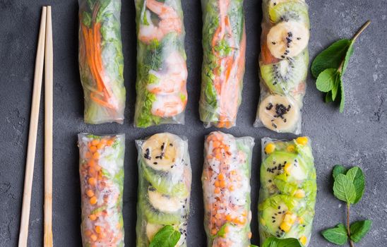 Fresh assorted spring rolls set. Handmade asian/Chinese spring rolls. Rustic concrete background. Spring rolls with shrimps, vegetables, fruits. Top view. Healthy asian food. Lunch/snacks/buffet