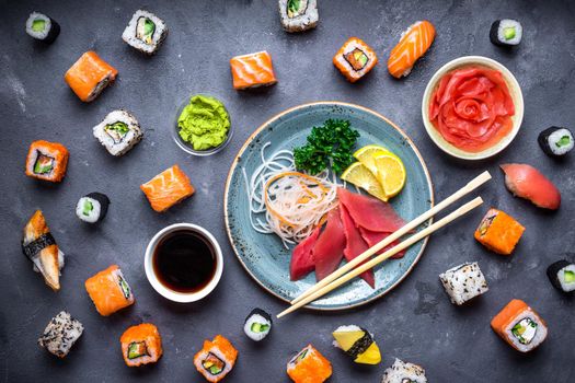 Japanese sushi on a rustic dark background. Sushi rolls, sashimi, nigiri, maki, pickled ginger, wasabi, soy sauce. Sushi set on a table. Top view. Asian or Japanese food. Sushi restaurant concept