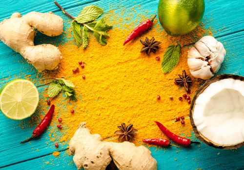 Thai food background. Ingredients for making thai food. Coconut, ginger, hot pepper, lime, curry, herbs, spices. Thai cuisine ingredients on blue wooden background. Space for text. Top view. Close-up