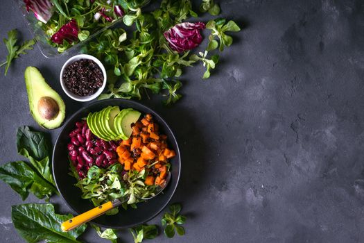 Quinoa salad in bowl with avocado, sweet potato, beans, herbs, spinat on concrete rustic background. Quinoa superfood concept. Clean healthy detox eating. Vegan/vegetarian food. Making healthy salad