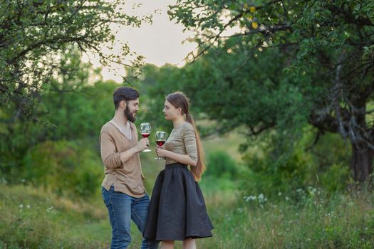 young couple drinking standing drinking wine from glasses being in nature