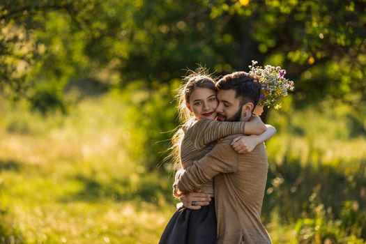 young couple hugging in nature, girl holding flowers