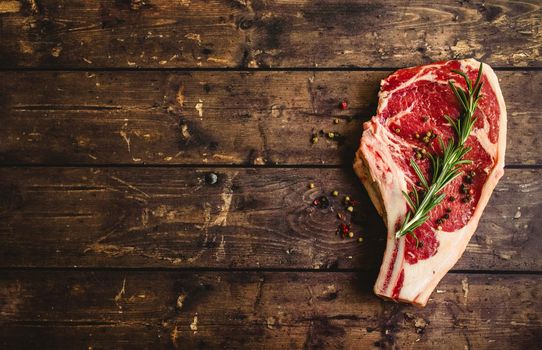 Raw marbled meat steak, pepper, herbs on rustic wooden background. Space for text. Beef Rib eye steak ready for cooking. Top view. Copy space. Ingredients for meat roasting. Ribeye meat steak. Closeup