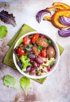 Healthy vegetarian salad with falafel, bulgur, olives, tomatoes, parsley. Healthy buddha bowl salad. Middle eastern style salad. Vegan/vegetarian food. Fresh lunch/dinner. Top view. Iron background