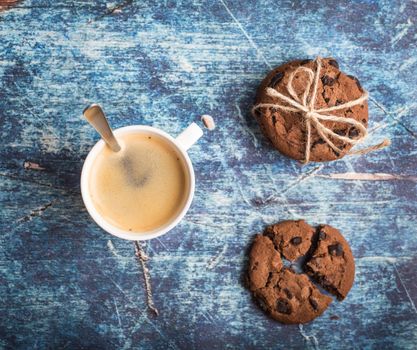 Cup of fresh hot coffee, chocolate cookies on old rustic blue wooden table. Vintage background. Morning coffee. Warm coffee, dessert for lunch. Espresso in white cup. Top view. Close up. From above