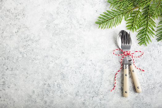 Christmas/New Year background. Christmas table place setting. Festive dinner background. Spoon, fork, fir branch on white concrete background. Christmas decoration. Space for text. Top view. Holidays