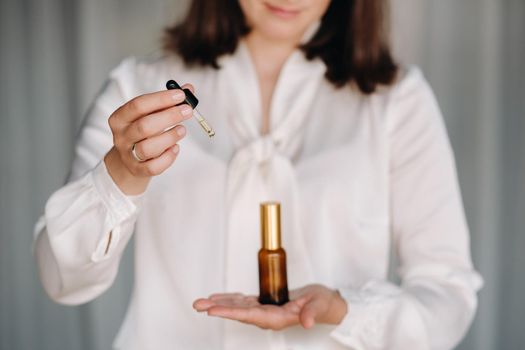 Close-up of female hands holding a bottle of essential oil, Aromatherapy.