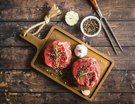Raw marbled meat steak Filet Mignon with seasonings, fork, wooden cutting board. Raw meat steak. Beef steak ready for cooking. Top view. Ingredients. Uncooked meat steak. Close-up. Rustic background