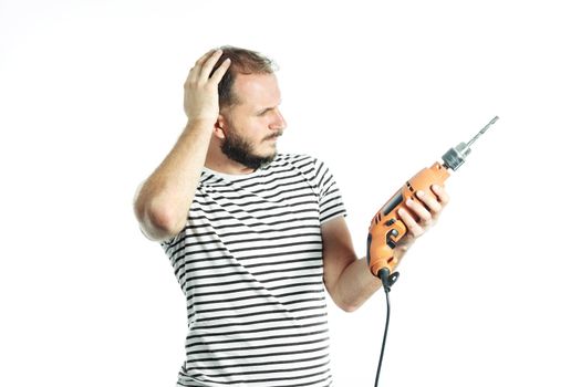 A working man in perplexity pondered look at a power tool - electric drill. Isolated on white.