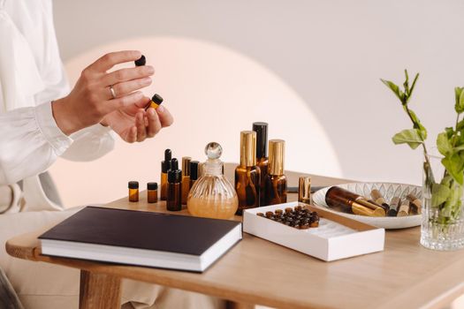 Close-up of a Woman's hands applying essential oil on her wrist indoors.