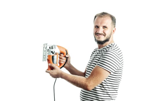 A smiling man in a striped T-shirt, holds an electric jigsaw in his hands. Isolated on white background.