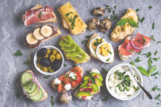 Assorted healthy sandwiches set background. Sandwich bar or buffet. Ciabatta sandwiches with dips, fish, cheese, meat, vegetables, fruits. Top view. Making sandwiches concept. Lunch time snacks