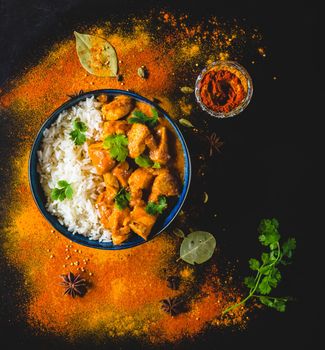 Indian Butter chicken with basmati rice, bowl, spices, black background. Indian style dinner. Butter chicken, traditional Indian dish. Top view. Chicken tikka masala. Indian cuisine concept. Overhead