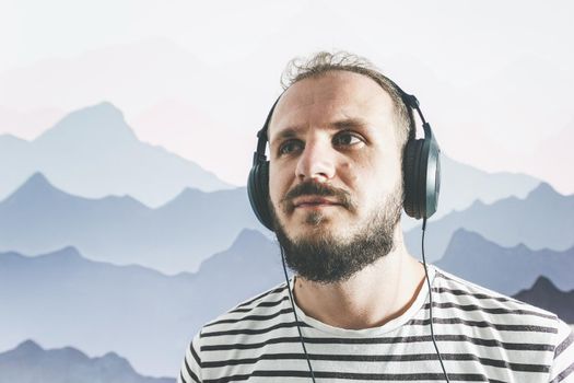 Meditative bearded happy man in a striped T-shirt listens to music with big headphones. looks to the top corner.