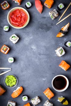 Japanese sushi on a rustic dark background. Sushi rolls, nigiri, maki, pickled ginger, wasabi, soy sauce. Sushi set on a table. Space for text. Top view. Sushi background. Asian or Japanese food frame