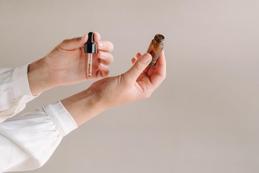 Close-up of a Woman's hands applying essential oil on her wrist indoors.