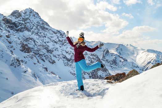 Beautiful happy young dancing woman on top of the mountain