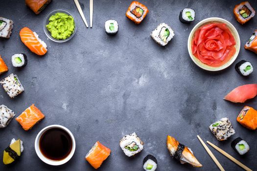 Japanese sushi on a rustic dark background. Sushi rolls, nigiri, maki, pickled ginger, wasabi, soy sauce. Sushi set on a table. Space for text. Top view. Sushi background. Asian or Japanese food frame