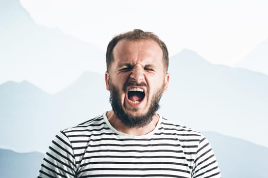 A screaming bearded man in a striped T-shirt. Emotional portrait.