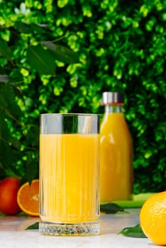 Glass of orange juice and orange juice bottles. Glass and bottle of organic tropical juice