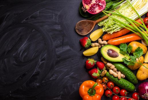 Vegetables, fruits, herbs, raw ingredients for cooking and spoon on rustic black chalk board background. Healthy, clean eating concept. Vegan or gluten free diet. Space for text. Top view. Food frame