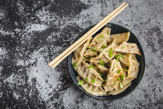 Asian dumplings in bowl, chopsticks, rustic stone background. Top view. Chinese dumplings for dinner. Closeup. Chinese dumplings for dinner/lunch. Traditional Asian/Chinese cuisine. Overhead. Dim sum