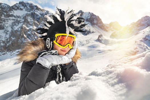 Cute young woman dressed in winter clothes portrait, glasses and winter funny hat, vacation on snow top of the mountain. Winter travelling scene, wanderlust concept.