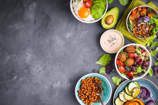 Mixed healthy vegetarian salads with vegetables, sweet potato, falafel, bulgur, avocado, eggs. Assorted buddha bowl salads background. Healthy dinner. Salad in bowl. Making ingredients. Space for text