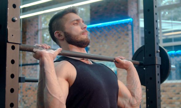 The male athlete lifting barbell. Bodybuilder in the gym