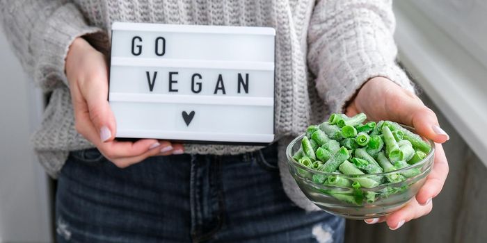 Lightbox with text GO VEGAN in female hands. Veganism, vegetarian healthy lifestyle. Frozen food in bowl. Healthy eating vegan. Green beans