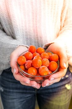 Female hands holding bowl with Frozen Cherry Tomatoes. Vegetable preservation. Harvest. Veganism, vegetarian healthy eating. Fitness diet