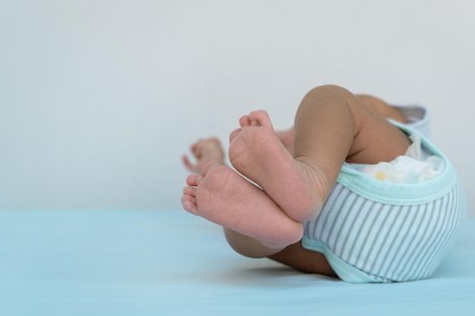 Photo of the feet of a 15-day-old newborn, lying on a blue diaper.